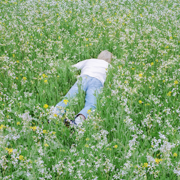 Man laying face down in field of long grass