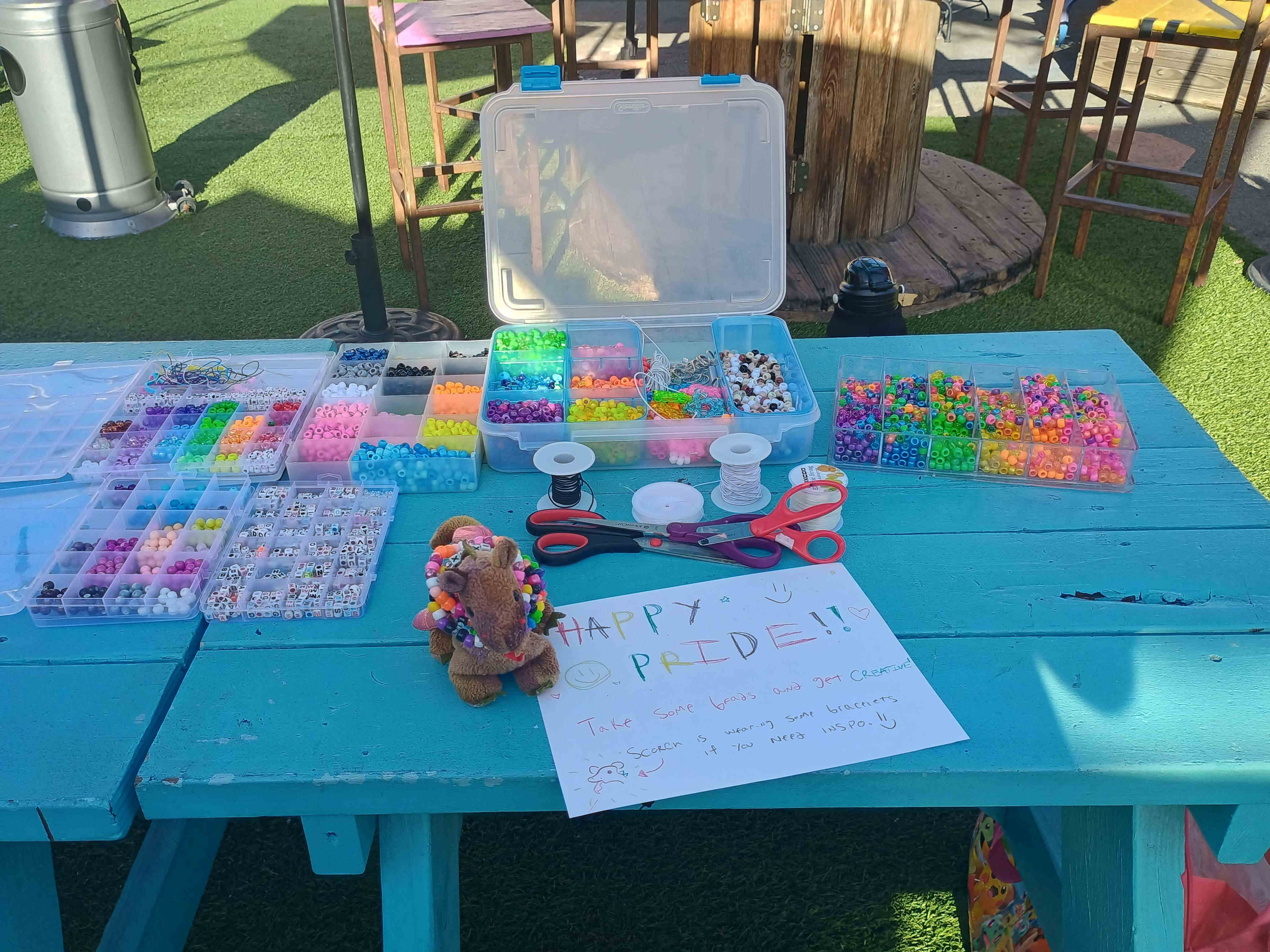 An outdoor picnic table with several boxes of plastic beads.